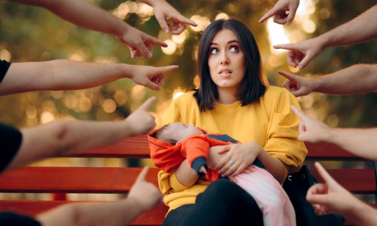 A woman being pointed at with many fingers holding a child - Kars4kids parenting blog